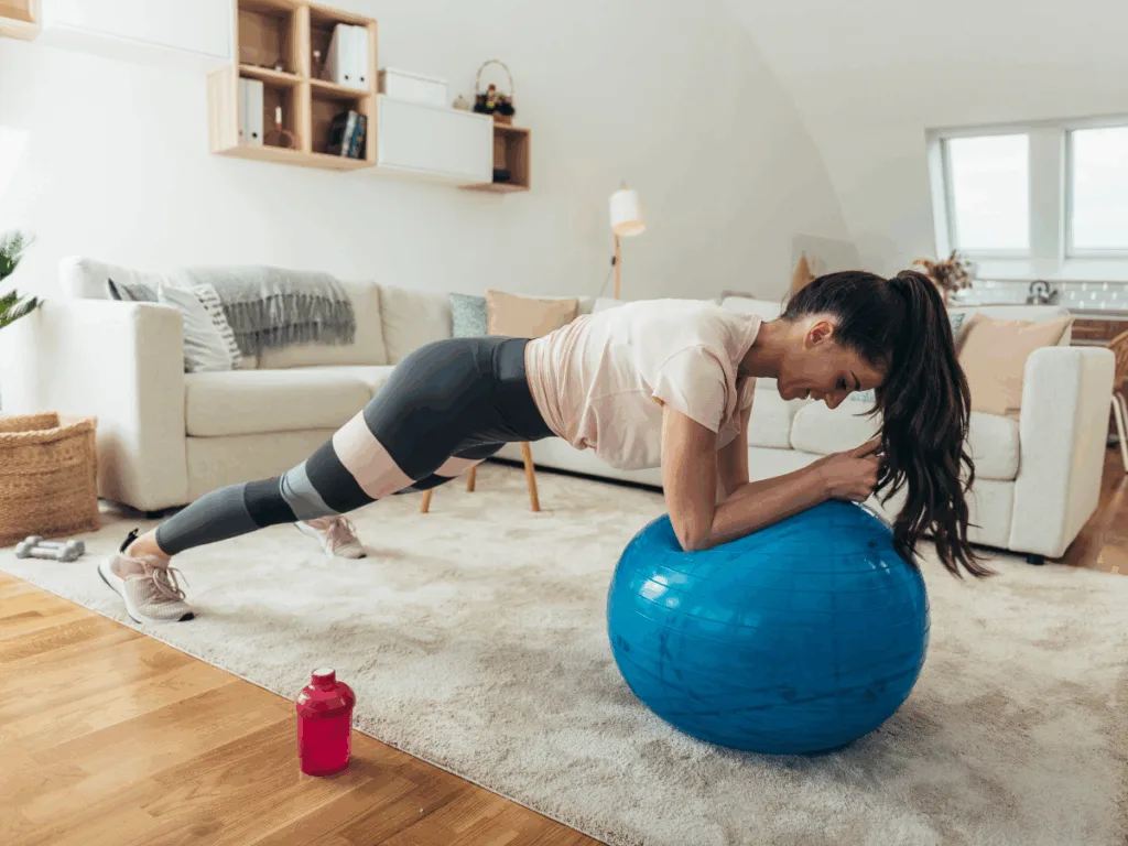Woman performing a plank on a Swiss ball at home to build core endurance and stability.